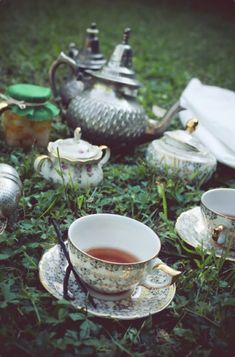 tea cups and saucers are sitting on the grass