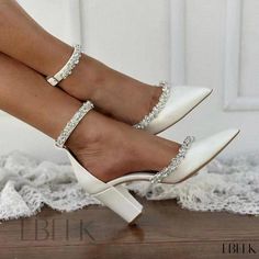 a woman's legs wearing white high heels with crystal straps and toe rings on them