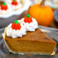 a slice of pumpkin pie on a plate with whipped cream and oranges in the background