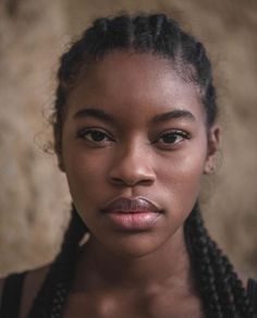 a woman with braids on her hair looking at the camera