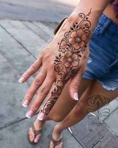 a woman's hand with henna tattoos on her left arm and the other hand