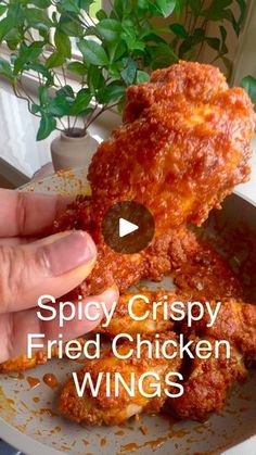 a person holding up a piece of fried chicken wings with the words spicy crispy fried chicken wings