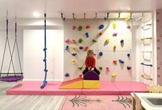 a woman sitting on top of a purple chair in front of a wall with climbing ropes