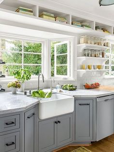 a kitchen filled with lots of white cabinets and counter top space next to a window