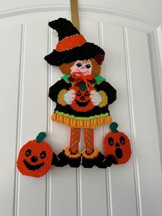 a cross stitch halloween decoration hanging on the front door