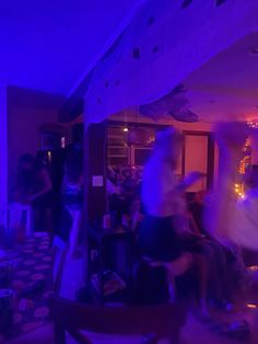 blurry image of people sitting in a room with purple lighting on the walls and floor