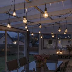 an outdoor dining area with lights hanging from the ceiling and patio furniture on the outside