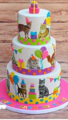 a three tiered cake with cats and balloons on the top is decorated in bright colors