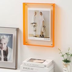 an orange frame hanging on the wall next to two magazines