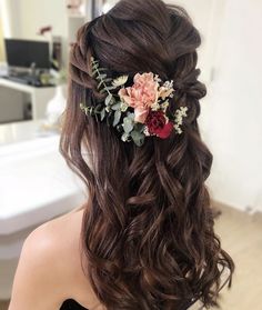 a woman with long brown hair and flowers in her hair is looking at the mirror