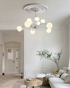 a living room filled with white furniture and a plant on top of a coffee table