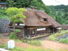 an old house with a thatched roof surrounded by greenery