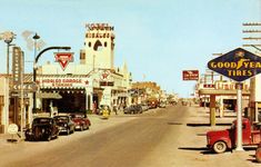 an old photo of cars parked on the street in front of buildings and signs that read goodyear tires