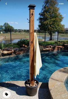 an umbrella stand next to a pool with a towel hanging from it's pole