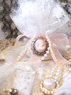 a close up of a brooch with pearls and laces on the table cloth