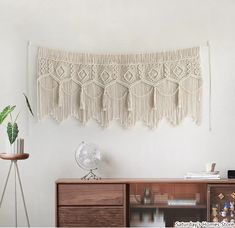 a white wall hanging next to a wooden dresser