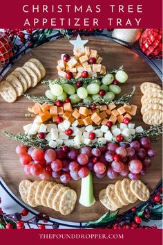 a christmas tree made out of crackers and cheese on a platter surrounded by holiday decorations