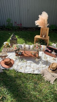 a table with hats and other items on it in the grass next to a fence