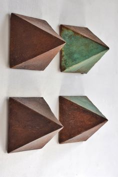 three pieces of metal on a white surface with green and brown shapes in the middle