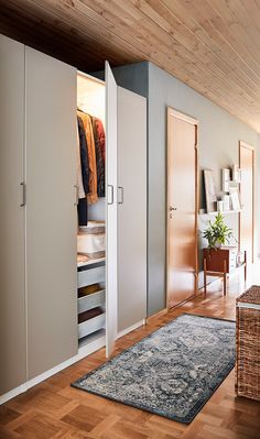 an open closet with clothes on hangers and a rug in front of the door