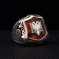 "Silver Albanian Eagle signet on the red pearl. There is illyrian shield symbol at the sides of the ring. Illyrians are considered to be the ancestors of the Albanian nation. This ring has Red Pearl Stone under the Albanian Double Head Eagle. I am designing a logo or symbol for you on the stone's empty area by use enamel work. Items has 1 year guaranty for the production mistakes. Stone: Red Pearl Material: Sterling Silver 925k and Bronze Plated: Rodium Plated Weight: 16.00gr Please make sure yo Shield Symbol, Albanian Eagle, Engraved Signet Ring, Shield Ring, Eagle Ring, Red Pearl, Pearl Stone, Best Gifts For Men, 22k Gold