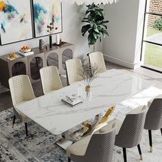 a dining room table with white chairs and a large painting on the wall behind it