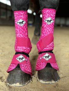 the legs and feet of a horse wearing pink boots with leopard print on it's sides