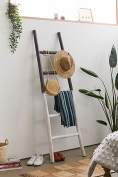 a ladder leaning up against a wall with hats on it and shoes hanging off the floor