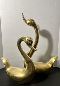 two golden metal birds sitting on top of a black table