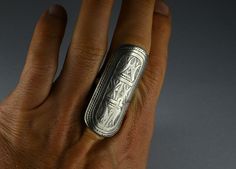 Antique silver ring composed of an oblong-shaped element depicting engraved designs with typical Tuareg geometric motifs. The front part of the ring measures 1.96 X 0.90 inch (50 x 23 mm) while the inner diameter measures 0.82 inch (21 mm). There is an antique silver mark on the backside of the ring visible in the 5th picture.  High quality silver and beautiful antique patina. Rare and collectible ring. Provenience: Mali. Ring Size (US): 12 Back to "Rings" section: https://www.etsy.com/shop/ArteOrientaleBologna?ref=hdr_shop_menu%C2%A7ion_id%C2%A7ion_id&section_id=18844837 Back to my shop: https://www.etsy.com/shop/ArteOrientaleBologna Traditional Silver Engraved Oval Ring, Traditional Silver Engraved Ring Oval Shaped, Traditional Silver Engraved Ring With Oval Shape, Silver Oval Engraved Ring, Traditional Silver Stamped Rings, Silver Etched Open Engraved Ring, Silver Engraved Open Ring With Etched Details, Engraved Silver Open Ring With Etched Details, Antique Silver Rings