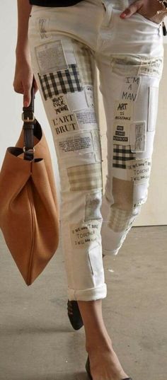 a woman in white jeans and black shoes holding a brown bag with newspaper print on it