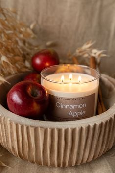 a candle and some apples in a bowl