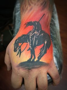 a person with a tattoo on their left hand holding a horse and rider in the sunset