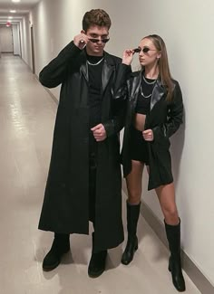 a man and woman standing next to each other in an empty hallway with white walls