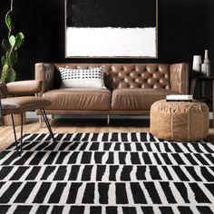 a black and white living room with leather couches, rugs and art on the wall