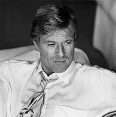 black and white photograph of a man sitting in a chair wearing a shirt and tie