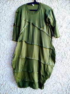 a green dress hanging on a wall with a hanger in front of the shirt