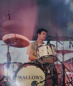 a man playing drums in front of a drum set on stage with the words wallows above him