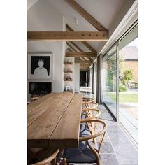 a long wooden table sitting under a window next to a wall with pictures on it