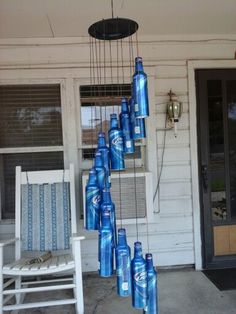 a bunch of blue bottles hanging from the side of a building next to a rocking chair