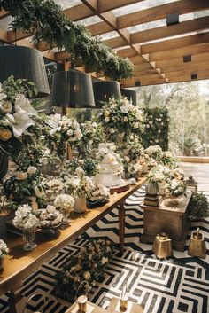 a room filled with lots of tables covered in flowers and greenery next to lamps