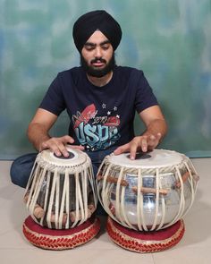 a man sitting on the floor playing with two large drum's in front of him