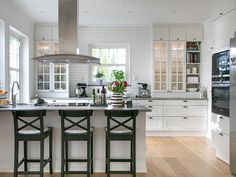 a kitchen with two bar stools in front of the island and an oven on the wall