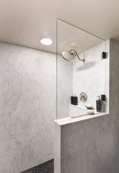 a bathroom with white marble walls and black tile flooring, along with a large mirror on the wall