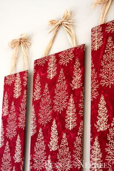 three red and white christmas cards hanging on a wall with twine ribbons attached to them