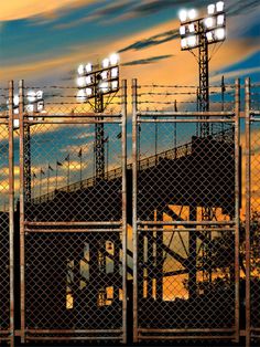 Rusty Chain Fence Stadium Backdrop - Rusty chain-link fence with barbed wire in front of a brightly lit stadium Rusty Chain, Chain Fence, Stadium Lights, Stadium Lighting, Friday Nights, Sports Stadium, Printed Photo, Promotional Image, Urban Industrial