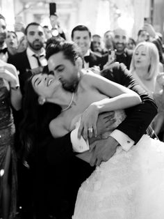 a bride and groom kissing in front of a crowd