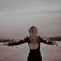 a woman standing in front of water with her arms outstretched