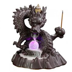 a statue of a dragon with a candle in it's mouth, holding a wand