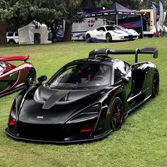 two black and red sports cars parked next to each other on a lush green field